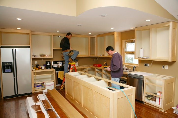 Two contractors renovating a kitchen, building new counters and cabinets.